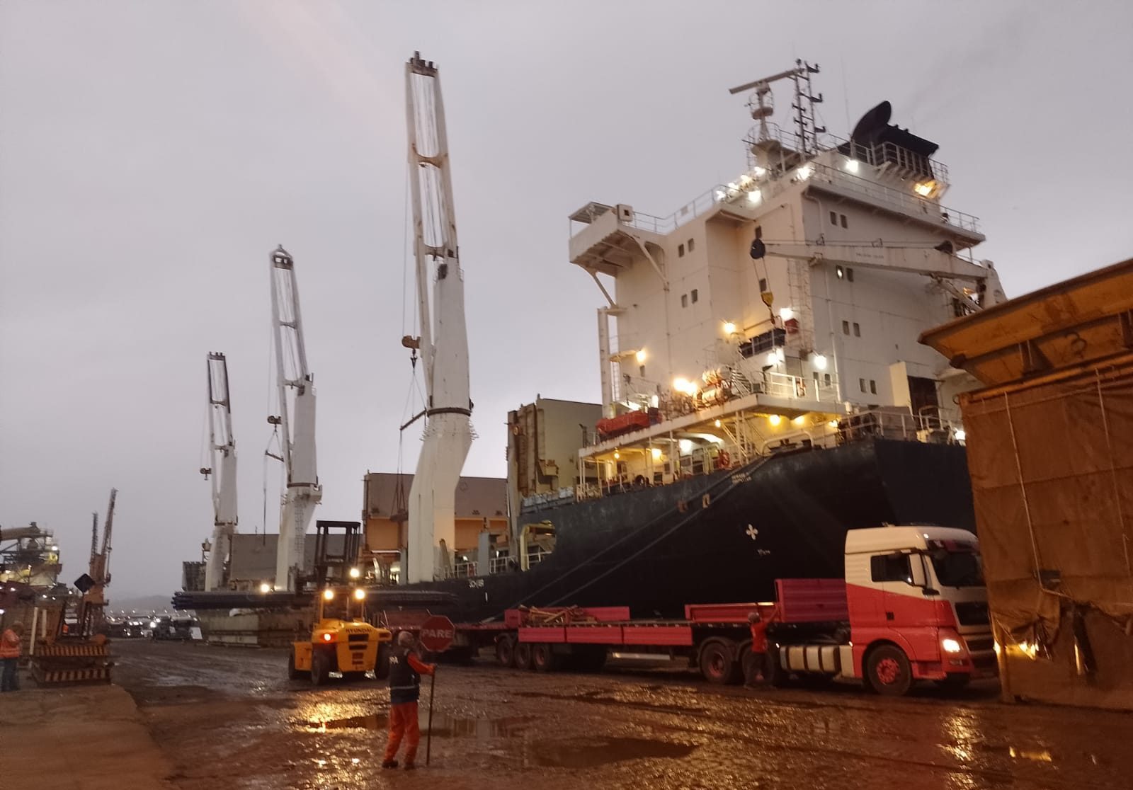 Guindastes portuários e navio em operação de embarque ao anoitecer